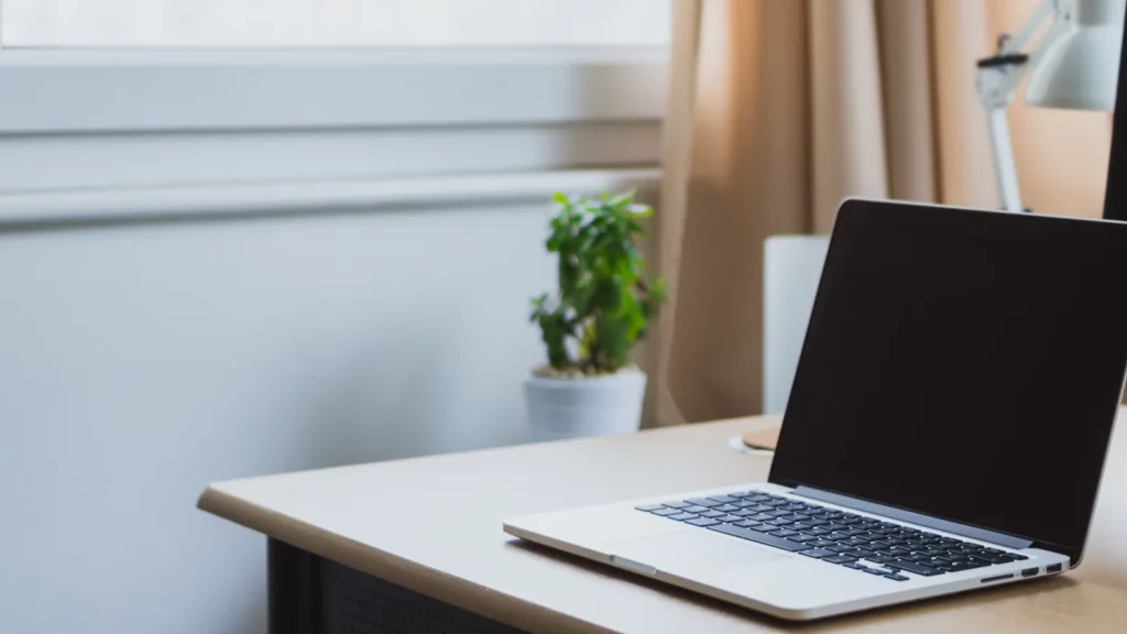 Ordinateur portable ouvert sur un bureau clair, prêt pour une vérification informatique avant les congés